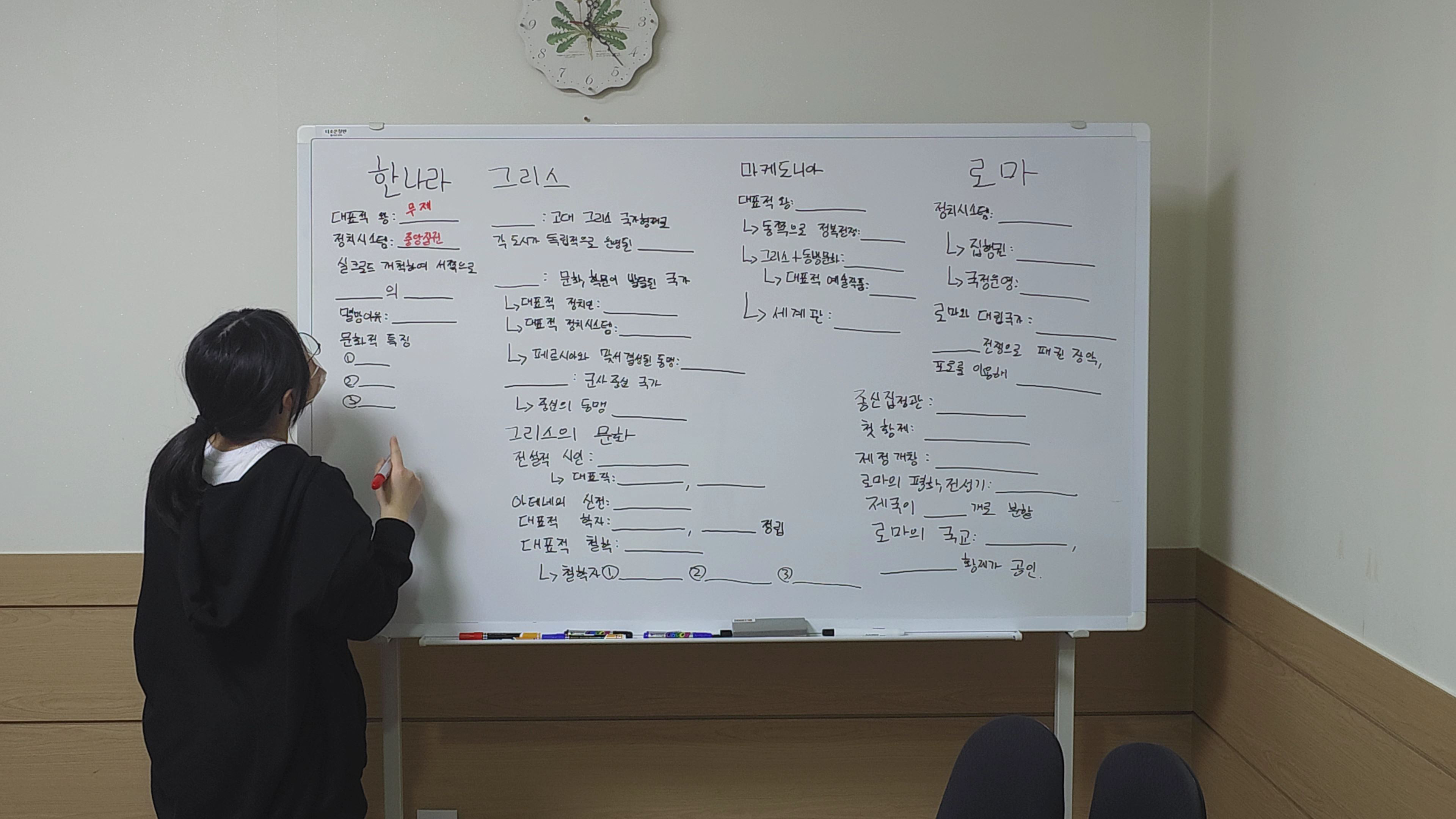 두비전 기존 역사 활동에서 학생이 화이트보드 앞에 선 장면. 정보를 펼쳐 놓고 활동하는 모습을 볼 수 있습니다.