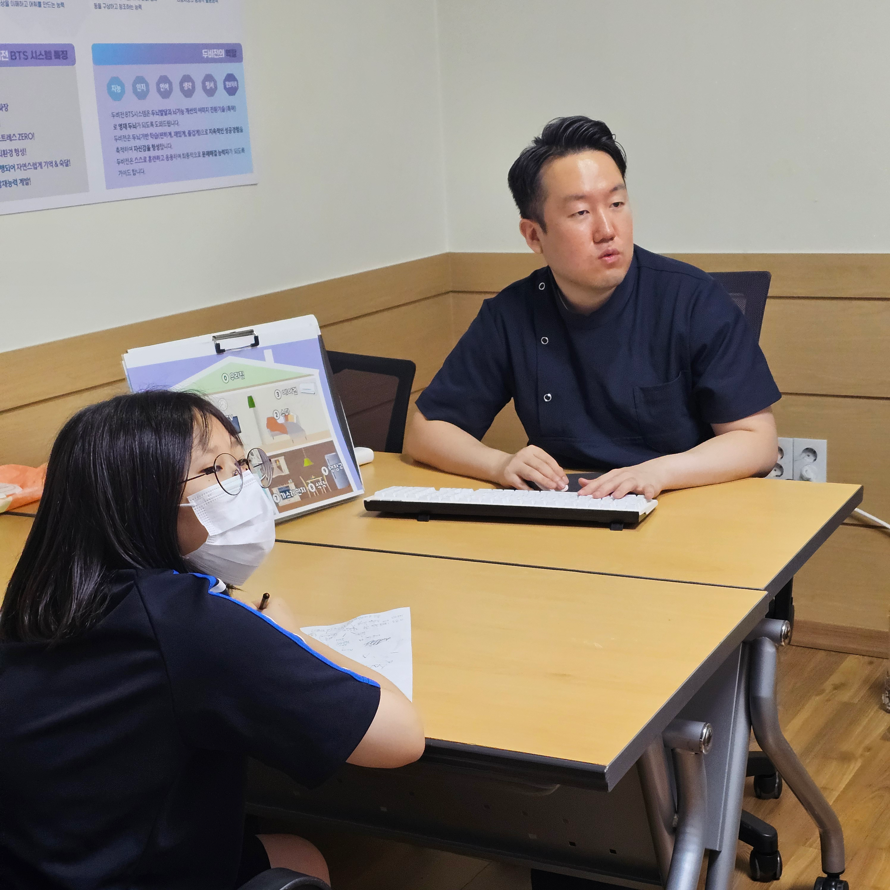 두비전 기존 수업에서 교사와 학생이 테이블에 마주 앉은 장면. 학생과 자료를 함께 볼 수 있는 교사의 자리를 참고할 수 있습니다.