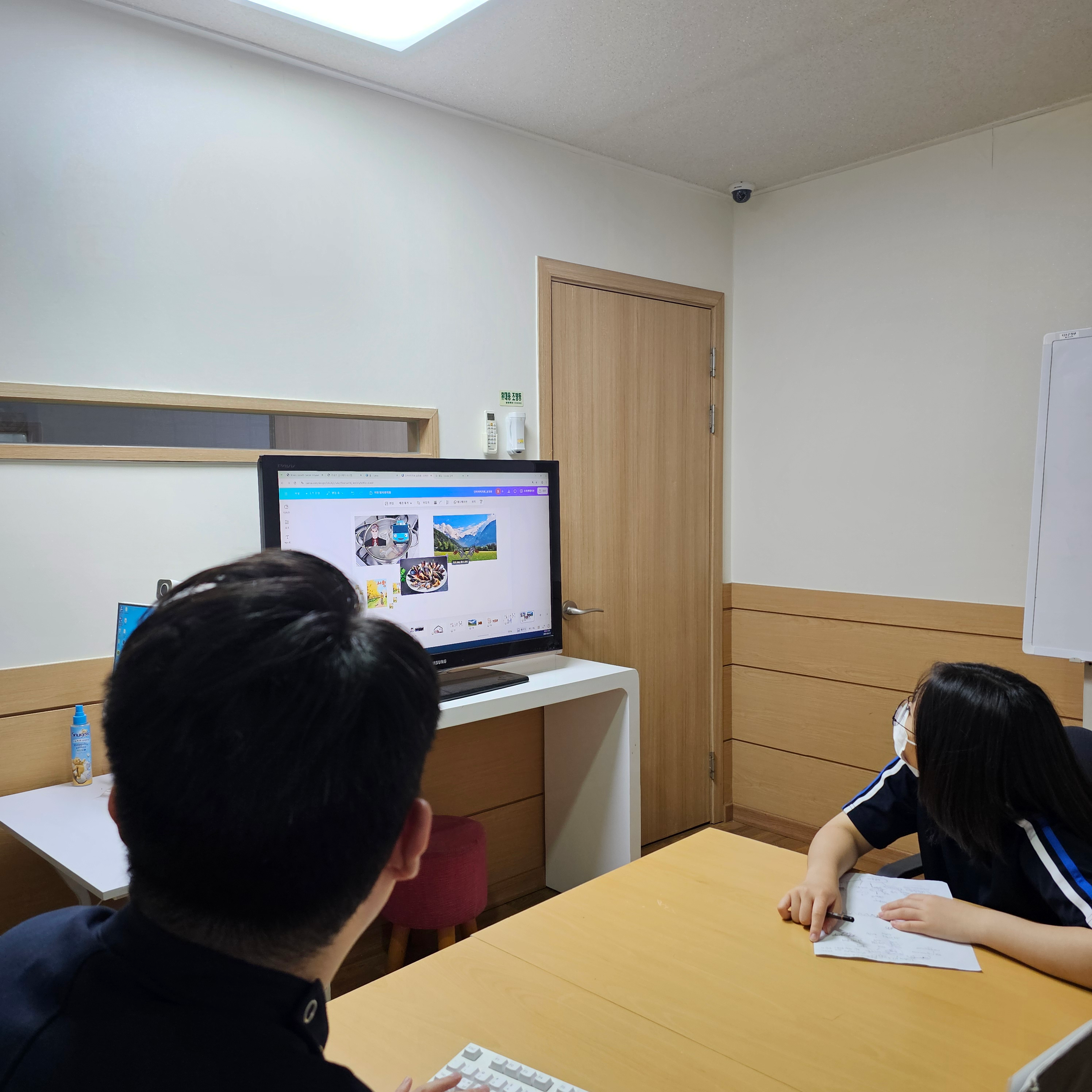 두비전 기존 수업에서 교사와 학생이 화면 옆에 앉은 장면. 설명하는 사람과 자료 사이의 거리를 살펴볼 수 있습니다.